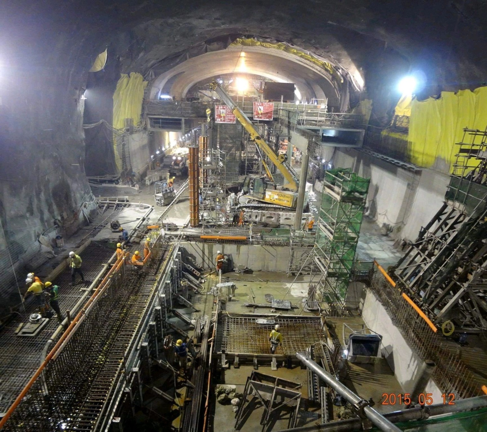 Underground metro station cavern under construction with scaffolding and cranes